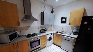 A compact kitchen with a gas stove, microwave, oven, washing machine, and dishwasher. - City Center Gem (Liverpool)