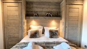 A wooden cabin-style bedroom with a bed, two pillows, and a fur throw. - Annapurna-appartement-6pers-proche centre (Les Gets)