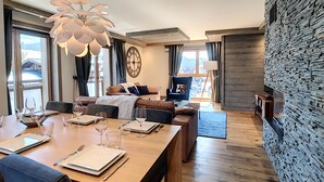 A modern living room with a wooden dining table set for four, a sofa, and a blue armchair. - Annapurna-appartement-6pers-proche centre (Les Gets)