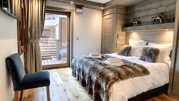 A bedroom with a bed, a chair, a wooden floor, a sliding door, and a wooden headboard. - Annapurna-appartement-6pers-proche centre (Les Gets)