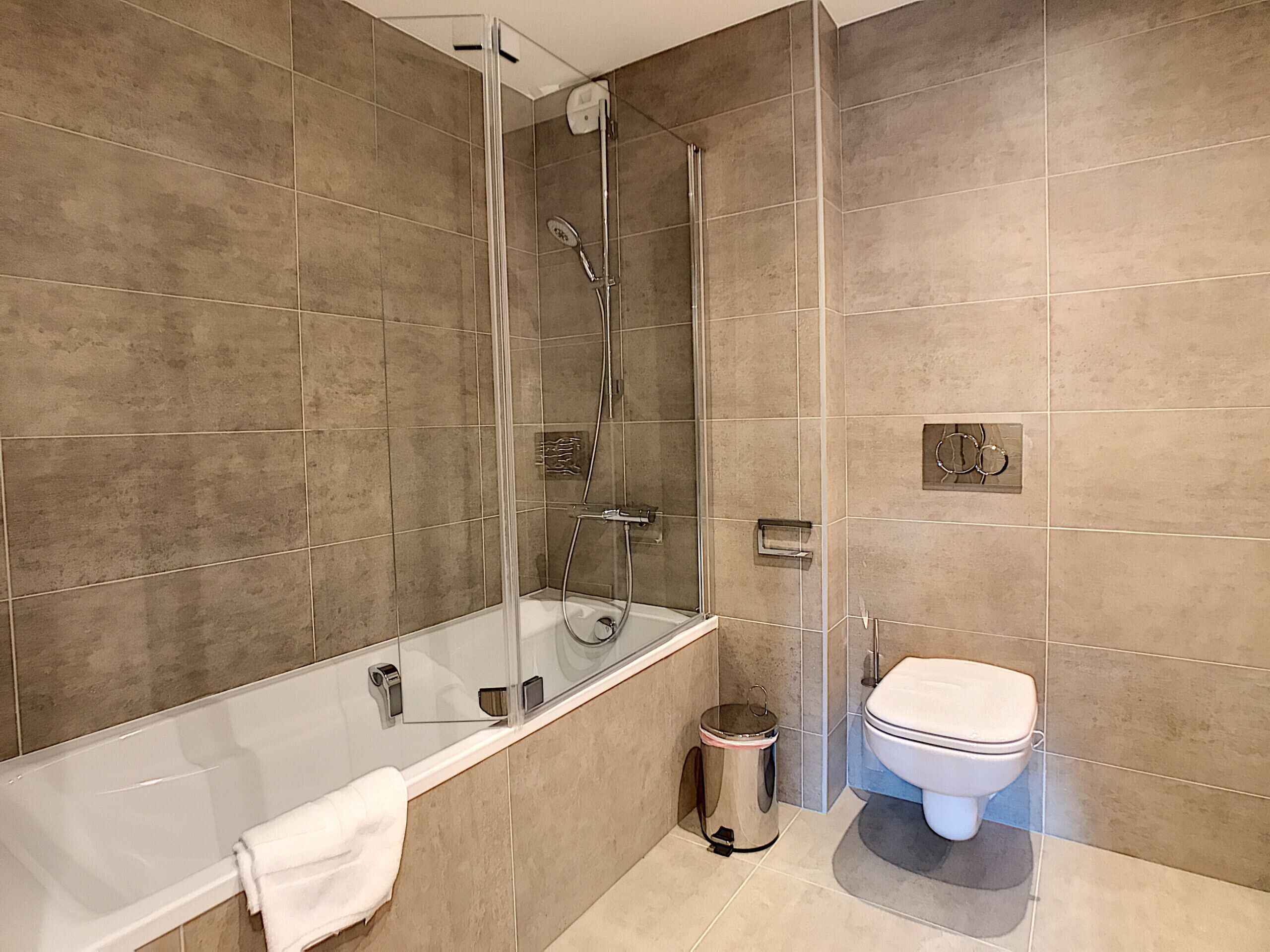 Une salle de bain moderne avec une douche à parois de verre, des toilettes séparées et une baignoire.