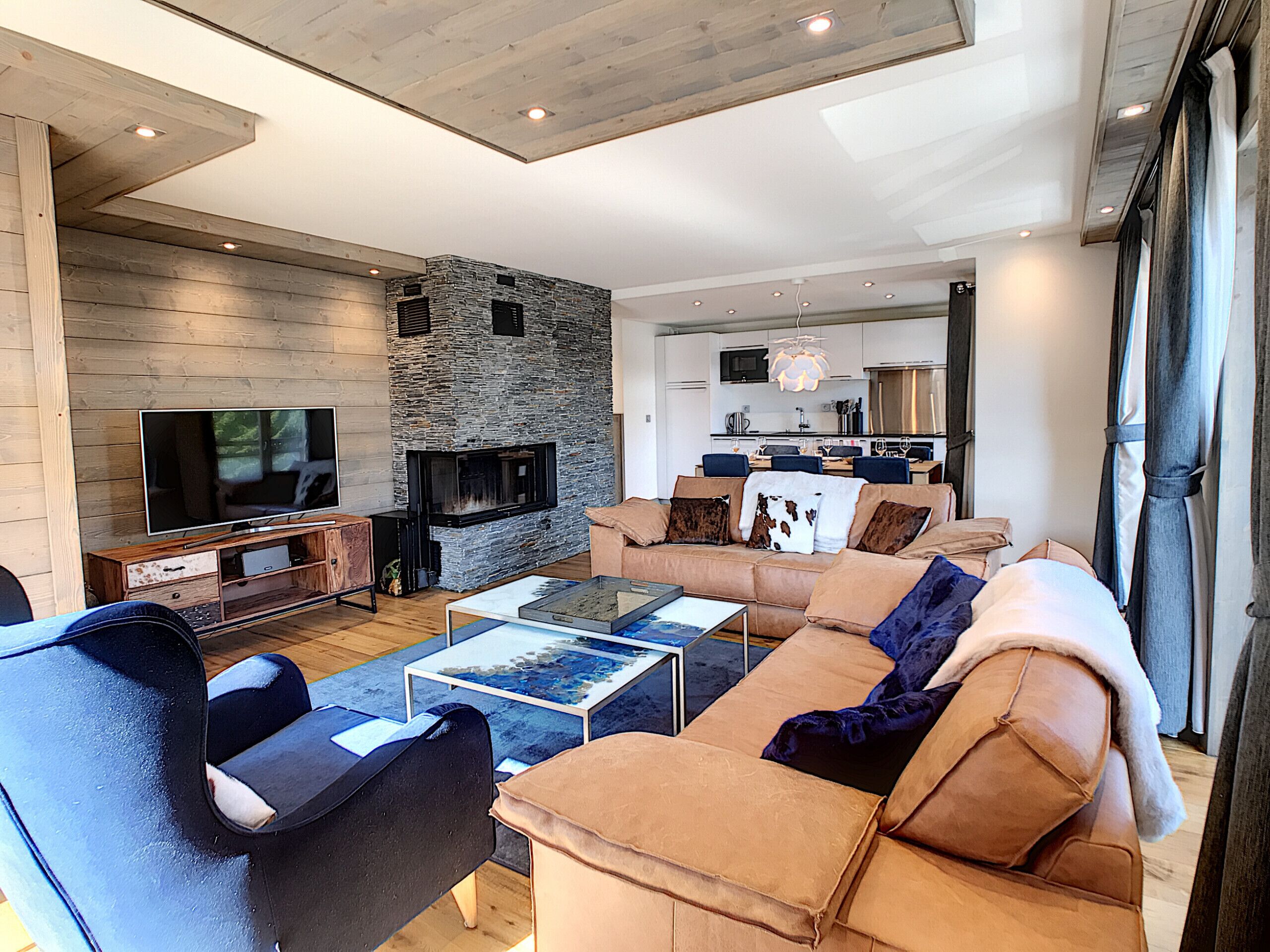 A modern living room with a stone fireplace, a TV, and a sofa.
