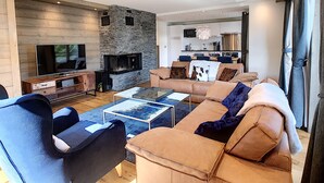 A modern living room with a stone fireplace, a TV, and a sofa. - Annapurna-appartement-6pers-proche centre (Les Gets)
