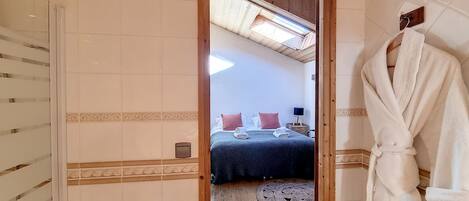 A bathroom with a wooden ceiling, a mirror, and a white robe hanging on the wall.