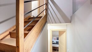 A wooden staircase with metal railings leading to a room with a bed and a door leading to another room. - La Bruyère - appartement - 6pers (Les Gets)