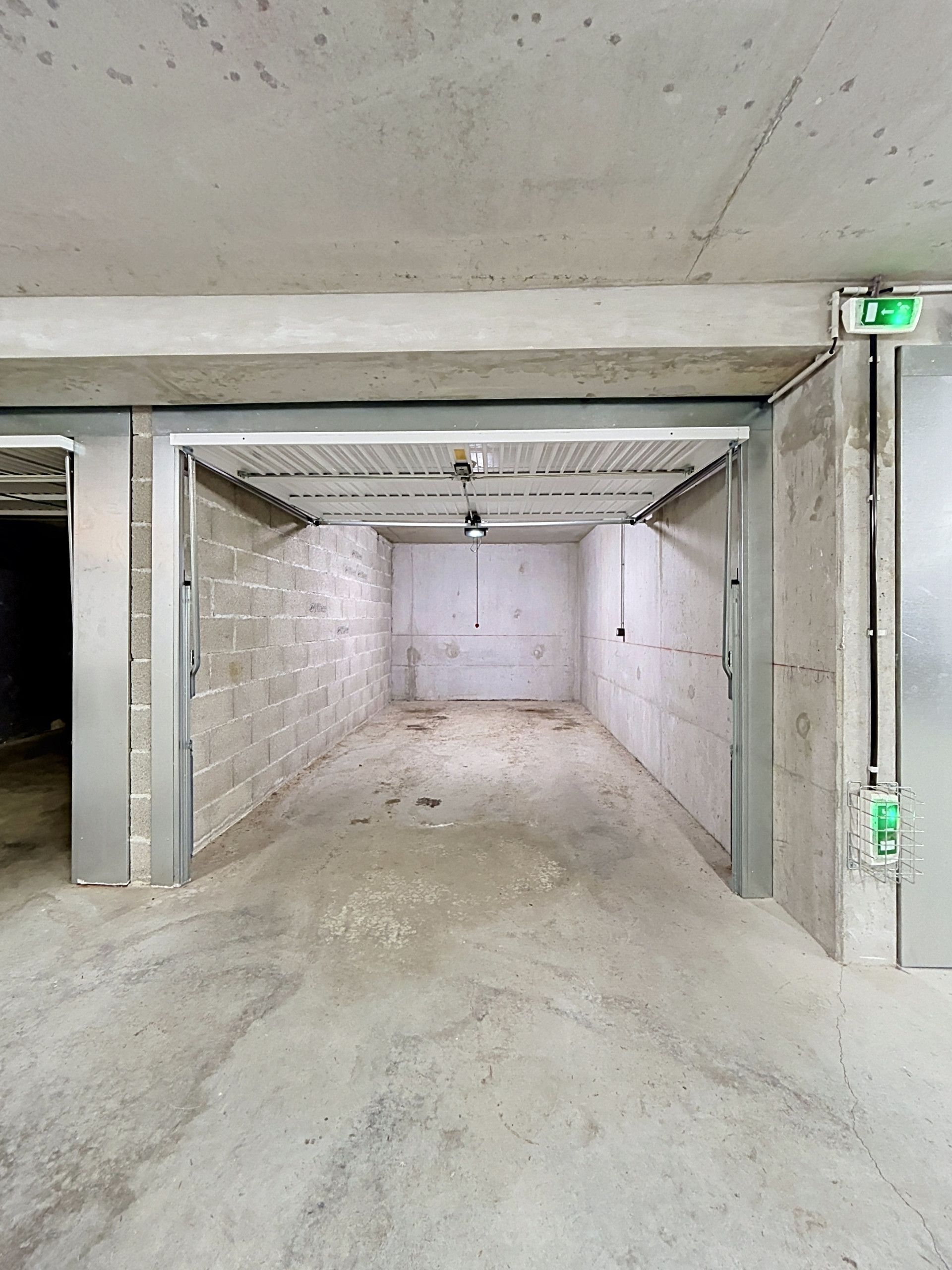 Ein Zimmer mit Betonwänden, Metalldecke und einem sichtbaren Notausgangsschild.
