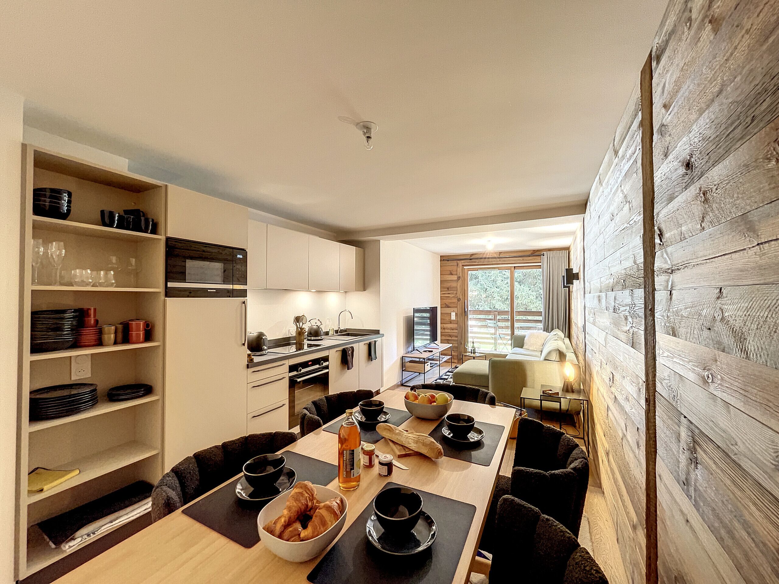 Een moderne keuken met een eethoek, houten wanden en uitzicht op de omgeving.