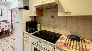 A kitchen with a stove, oven, and coffee maker. - Clos 11 - appartement - 8 pers - proche centre (Les Gets)