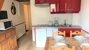 Una cocina compacta con gabinetes rojos, microondas, tostadora y cafetera.