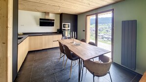 Una cocina moderna con techo de madera, una mesa de comedor con sillas y vistas a través de un ventanal.