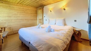 A wooden-paneled room with a bed, two wall-mounted lamps, and a small wooden table. - Chalet Leonie - 10 pers - proche centre (Les Gets)