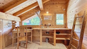 A wooden cabin with a kitchen area including a sink, a window, and a ladder. - Chalet Leonie - 10 pers - proche centre (Les Gets)