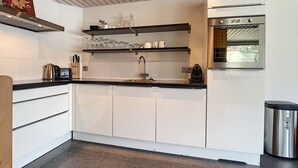 Une cuisine moderne avec des armoires blanches, une hotte de cuisinière en acier inoxydable et un four encastré.