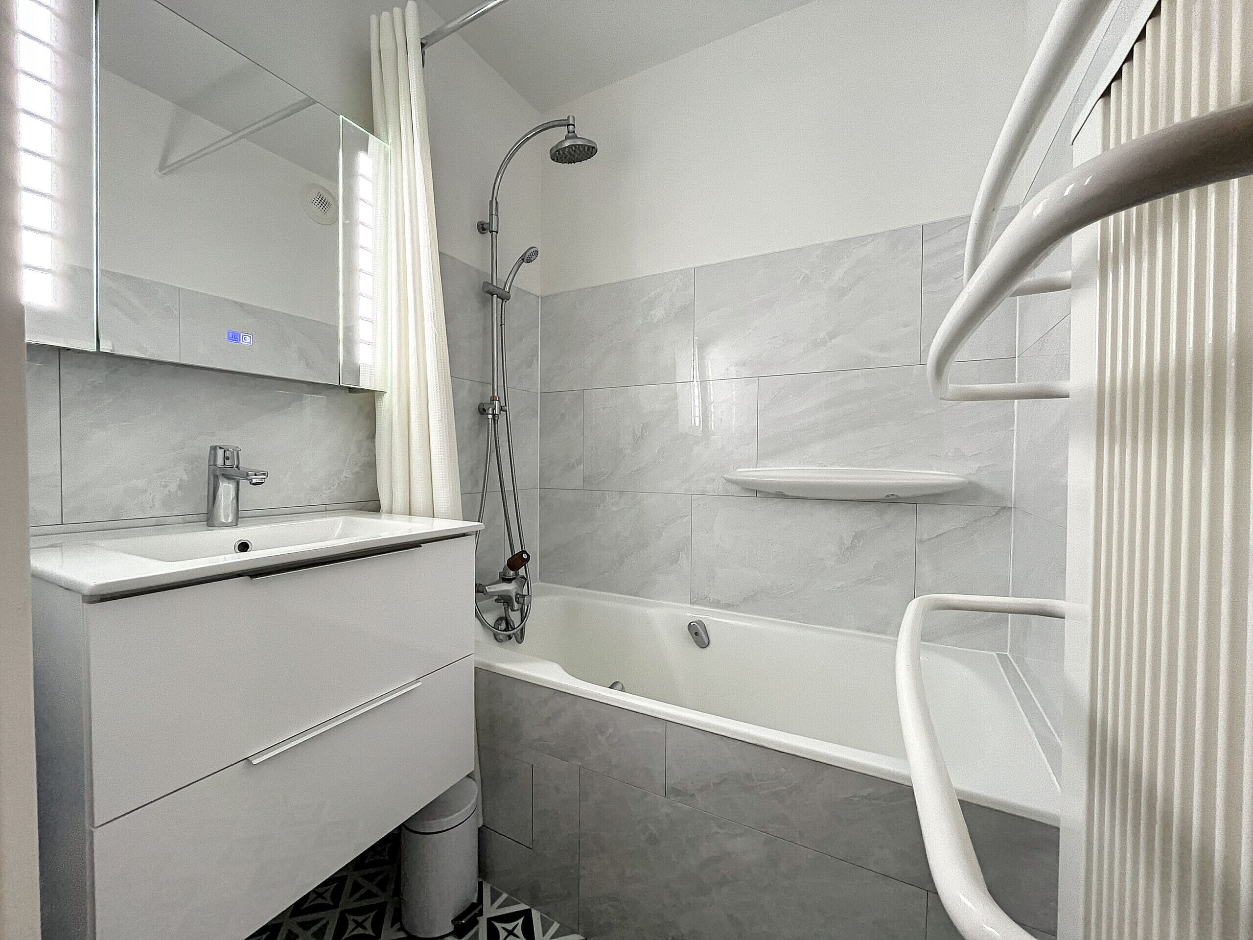 Une salle de bain moderne équipée d’une baignoire, d’une douche et d’un lavabo.