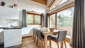 Une cuisine moderne avec un coin repas, un plancher en bois et de grandes fenêtres avec des rideaux.