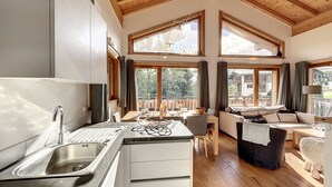 Une cuisine moderne avec un évier, un plafond en bois et de grandes fenêtres.