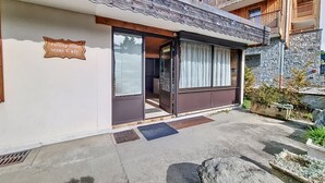 Un bâtiment avec une enseigne indiquant « Parking privé Mont Caly », une entrée avec une porte en verre et une façade en pierre.