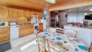 L’intérieur d’un chalet en bois comprend une cuisine, un coin repas et une grande fenêtre.