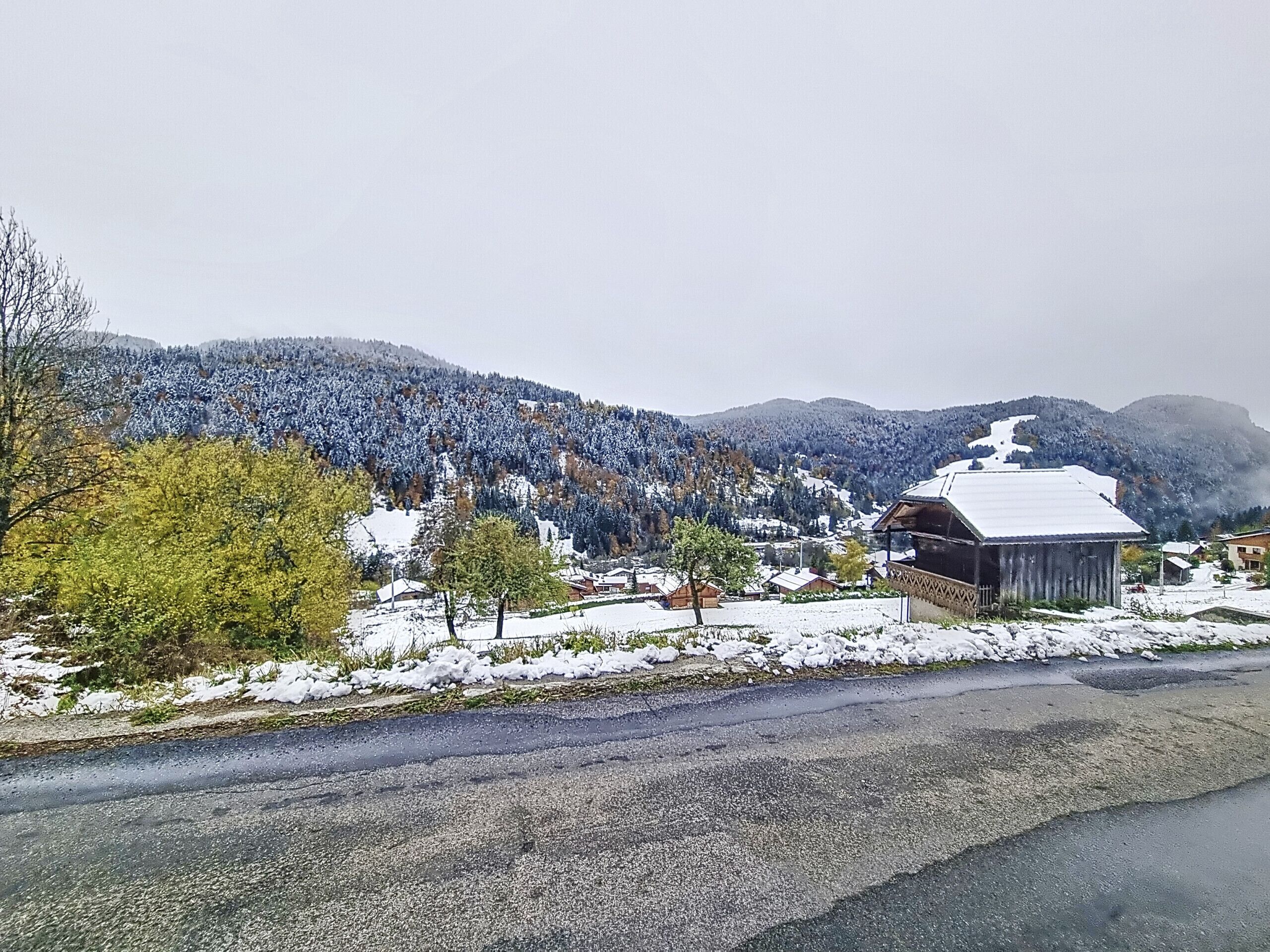 Eine ländliche Gegend mit verschneiter Landschaft, einer Straße und einem Gebäude mit schneebedecktem Dach.
