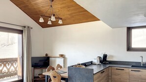 A modern kitchen with wooden cabinets, a built-in island, and a wooden ceiling. - Cornuts 2 - appartement -5pers (Les Gets)