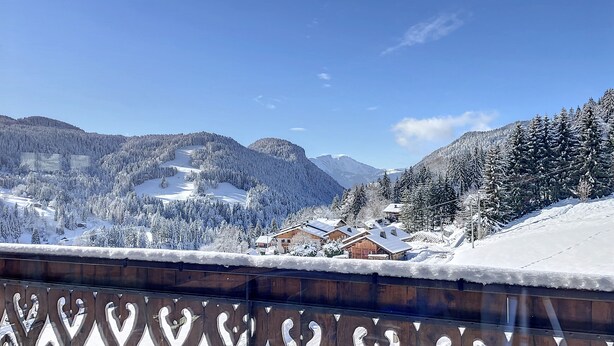 A snow-covered mountain landscape with wooden buildings and a wooden fence with heart-shaped cutouts. - Cornuts 3 - appartement - 7pers (Les Gets)