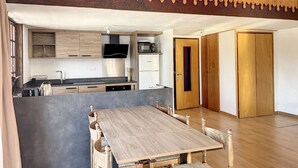 A modern kitchen with wooden cabinets, a flat-screen TV, and a dining area with a wooden table and chairs. - Cornuts 3 - appartement - 7pers (Les Gets)