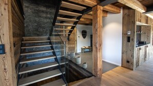 A wooden staircase with a glass railing leading to a stone wall. - Chalet Caly - 15pers - vue montagne (Les Gets)