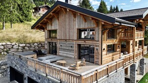 A two-story wooden cabin with a deck, stone walls, and a view of a mountainous landscape. - Chalet Caly - 15pers - vue montagne (Les Gets)