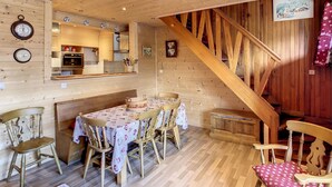 A wooden interior with a dining table, chairs, a kitchen area, and a staircase. - Edelweiss- appartement - 7pers -proche centre (Les Gets)