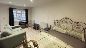 Ein Schlafzimmer mit einem Bett, einer Couch, einem Schreibtisch und einer Heizung.