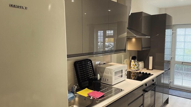 Eine moderne Küche mit einem Samsung-Kühlschrank, einer Mikrowelle, einem Toaster und einem Wasserkocher auf der Arbeitsfläche.