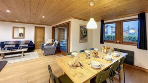 Un interior de madera con una mesa de comedor preparada para cuatro personas, un sofá y una silla.