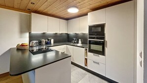 Una cocina moderna con una isla central, electrodomésticos integrados y techo de madera.