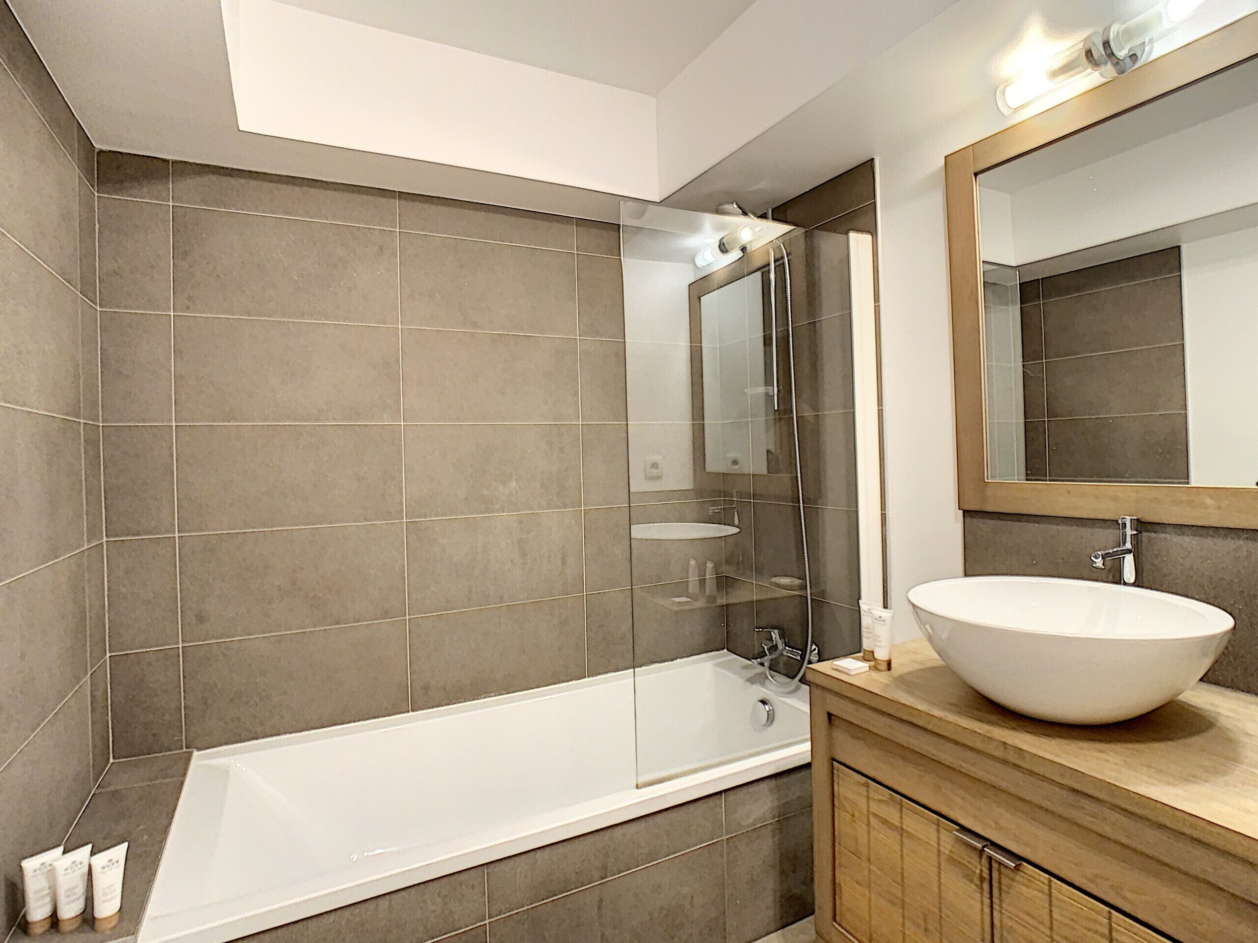 A modern bathroom with a large bathtub, a vanity with a large sink, and a mirror above the sink.