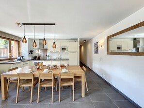 A modern kitchen with white cabinets, a central island, and pendant lighting. - Le K2  1- appartement- 6pers -proche pistes (Les Gets)