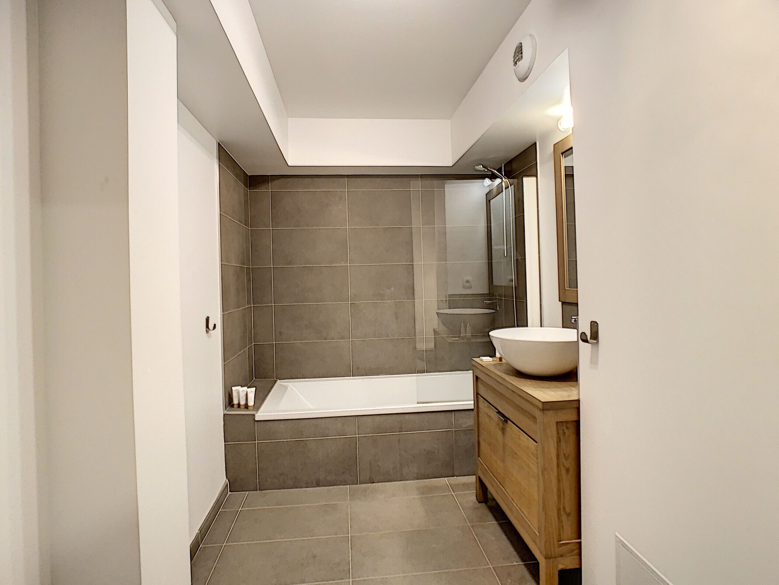 Ein modernes Badezimmer mit einer Badewanne, einem Holzbadezimmer-Möbel und einem großen Spiegel.