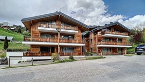 En toetagers trælodge med balkoner, en belagt indkørsel og en bil foran.