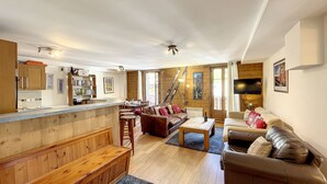 A spacious living area with a wooden bench, a sofa, a coffee table, and a dining table.