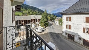 A balcony with a view of a street, buildings, and mountains.