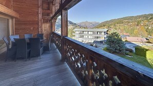 Ein Holzbalkon mit Blick auf eine Berglandschaft und Gebäude.