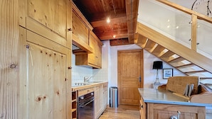 Eine Holz-Küche mit Holztür, Spüle und Mülleimer.