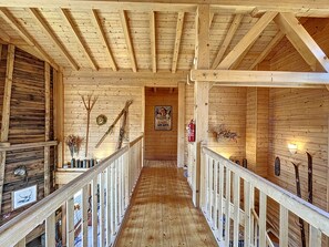 Cozy cabin-style interior with a central staircase, wooden walls, and rustic charm.
