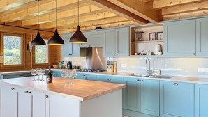 Eine moderne Küche mit hellblauen Schränken, einer Holzbalkendecke und Pendelleuchten.