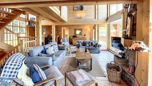 Eine geräumige Holzhütte mit hohen Decken, einem Kamin und einem großen Fenster mit Blick ins Freie.
