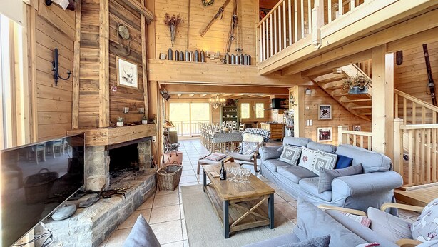 Eine geräumige Holzhütte mit Kamin, Essbereich und Wohnzimmer mit Sofa und Couchtisch.