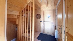 A wooden interior with a staircase, a door with a diamond-shaped window, and a tiled floor. - Chalet Noisette -8 pers - proche centre (Les Gets)