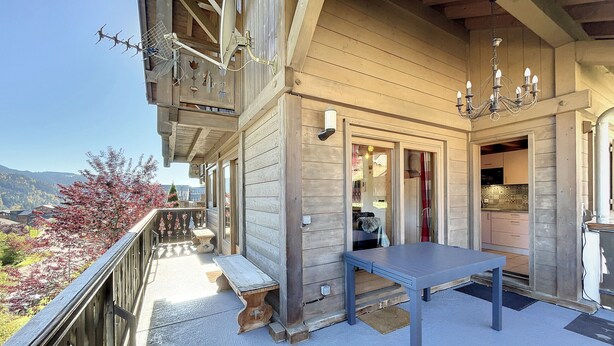 A wooden building with a balcony, a table, and a bench. - Chalet Noisette -8 pers - proche centre (Les Gets)