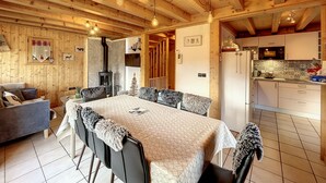 A cozy wooden cabin interior with a dining area, kitchen, and a fireplace. - Chalet Noisette -8 pers - proche centre (Les Gets)