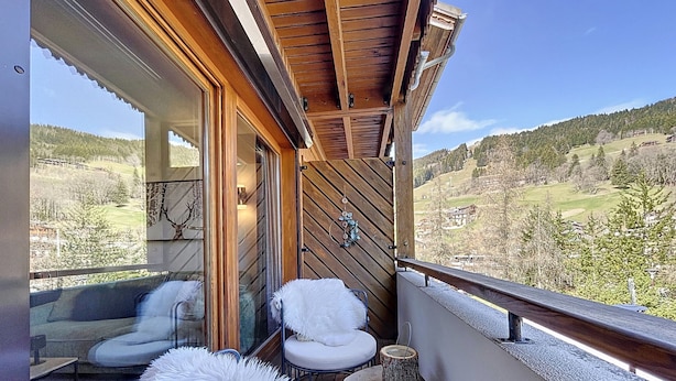 A balcony with two white cushioned chairs, a small table, and a view of a mountainous landscape. - Les 3 Sapins - appartement4pers - centre station (Les Gets)