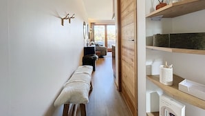 A hallway with a bench, wooden shelves, and a door leading to a balcony. - Les 3 Sapins - appartement4pers - centre station (Les Gets)